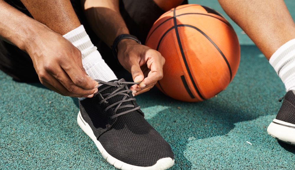 man tying sports shoes in basketball court