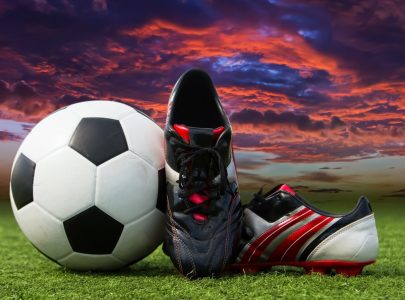 soccer ball and soccer shoes on the field of green grass