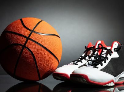 man tying sports shoes in basketball court