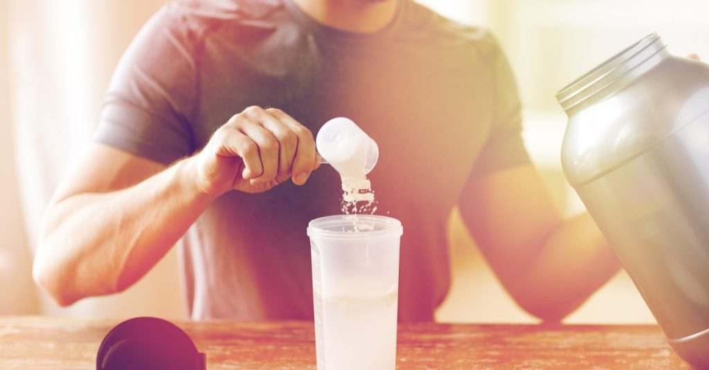 man with jar and bottle preparing protein shake