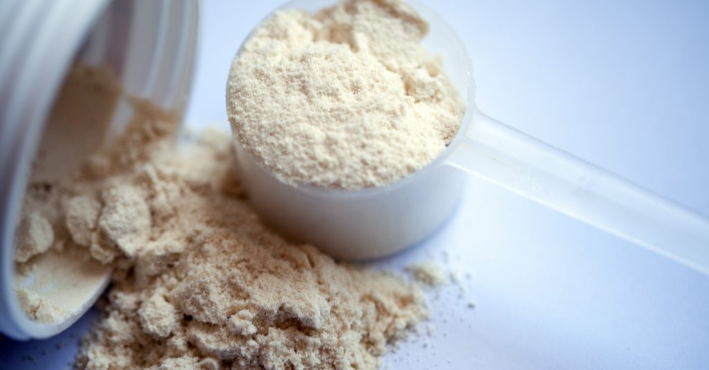 vanilla protein powder in scoop on white background
