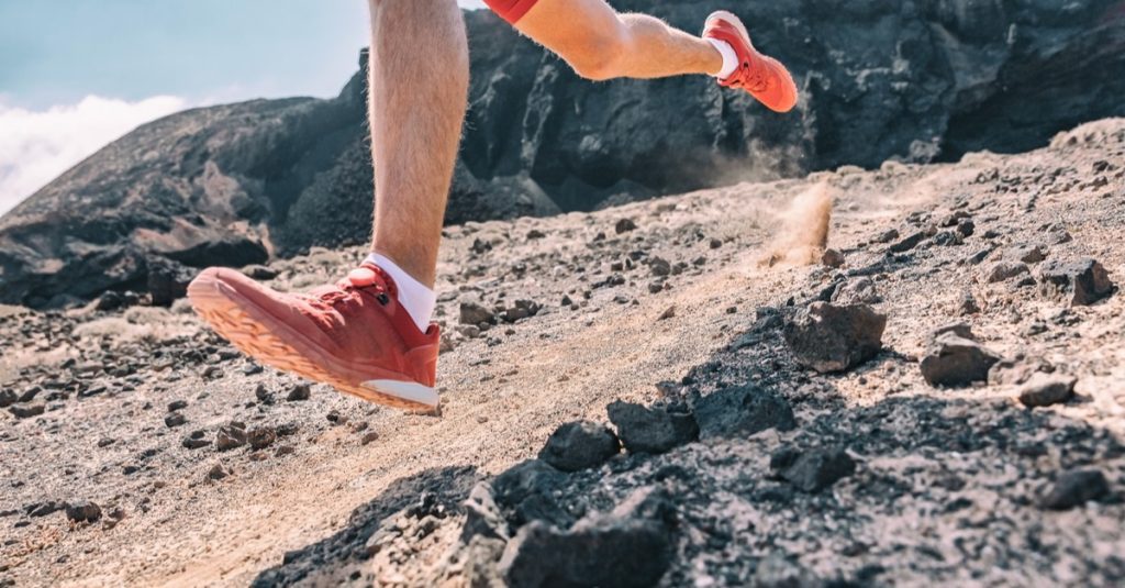 running man on exercising racing fast on volanic trek path in mountain