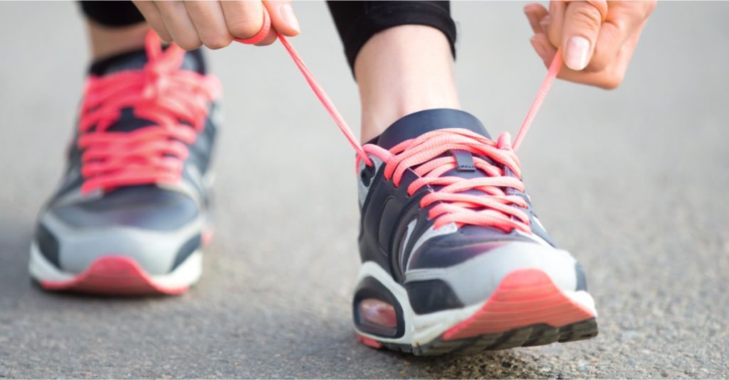 women hand tying running shoes